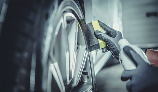 A person wearing gloves applies ceramic wheel protectant while polishing a car tire to enhance its protection and appearance.